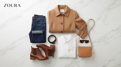 Flat lay of a camel wool coat, white shirt, dark denim and brown leather boots